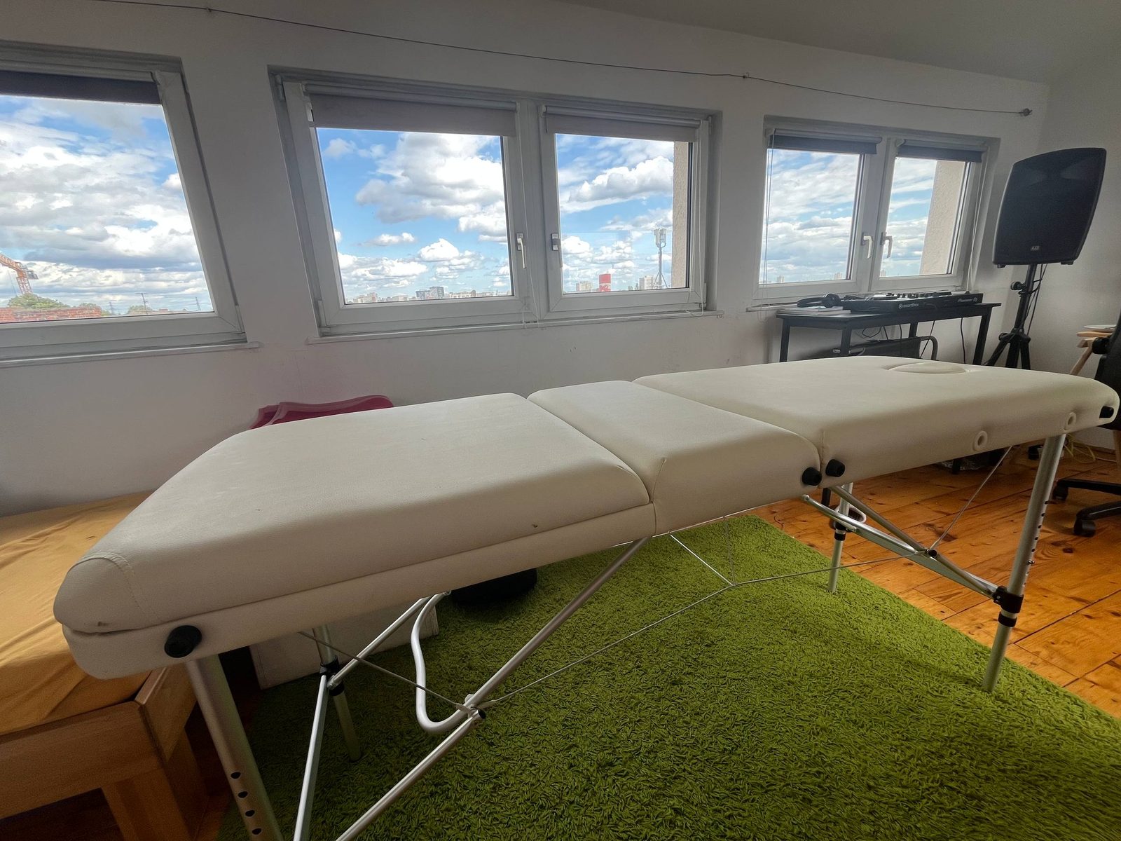 The studio: a treatment table beside a wall of windows looking out over the city sky.